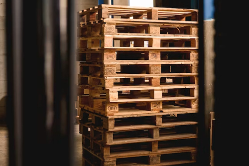 imagen de una operario de logística, con casco, en un almacén cargando una caja.